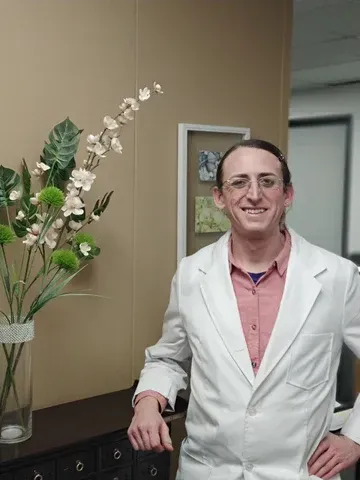 Dr. Davina standing in front of a vase of flowers in a white lab coat