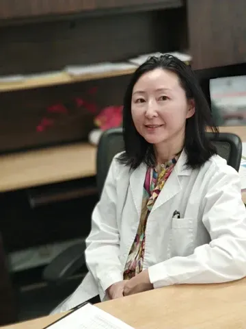 Dr. Ge sitting at her desk in a white lab coat