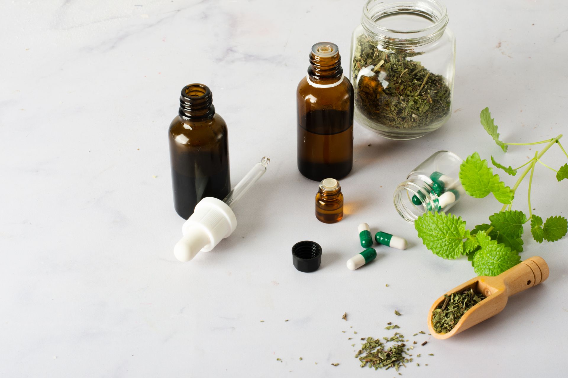 A bottle of essential oil next to a jar of dried herbs