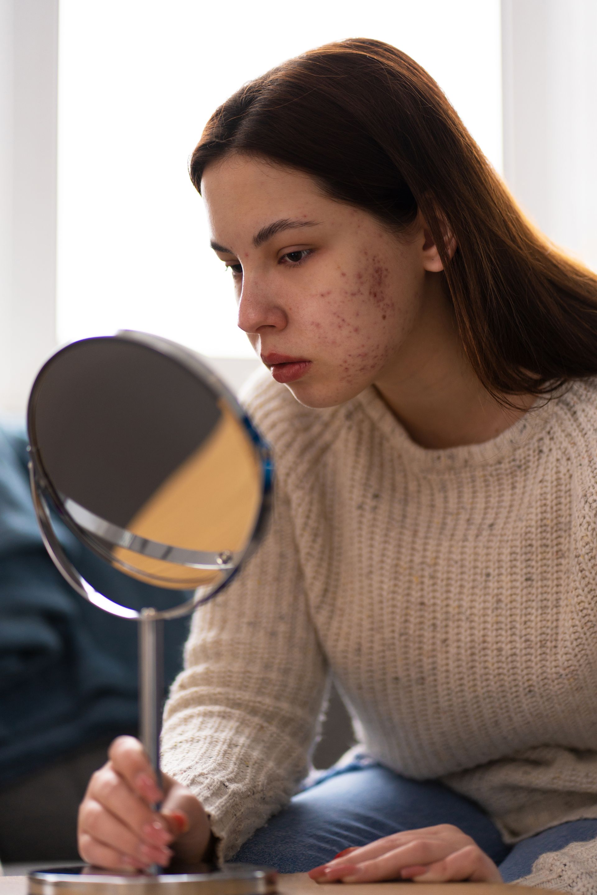Person examining their skin in a mirror