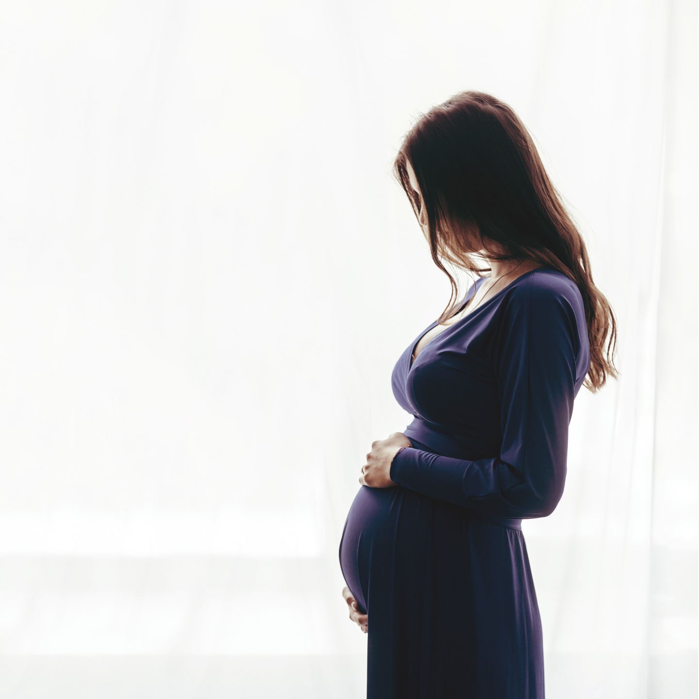 Pregnant woman standing against a window