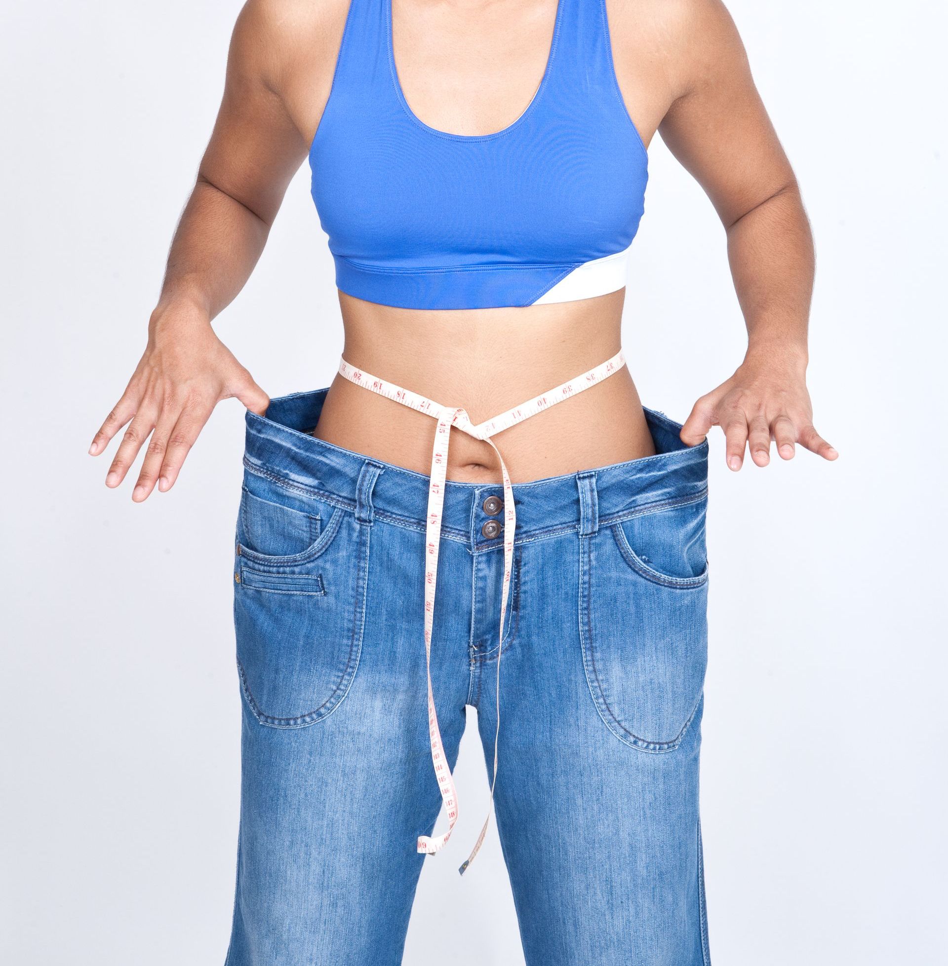 A woman is measuring her waist with a tape measure
