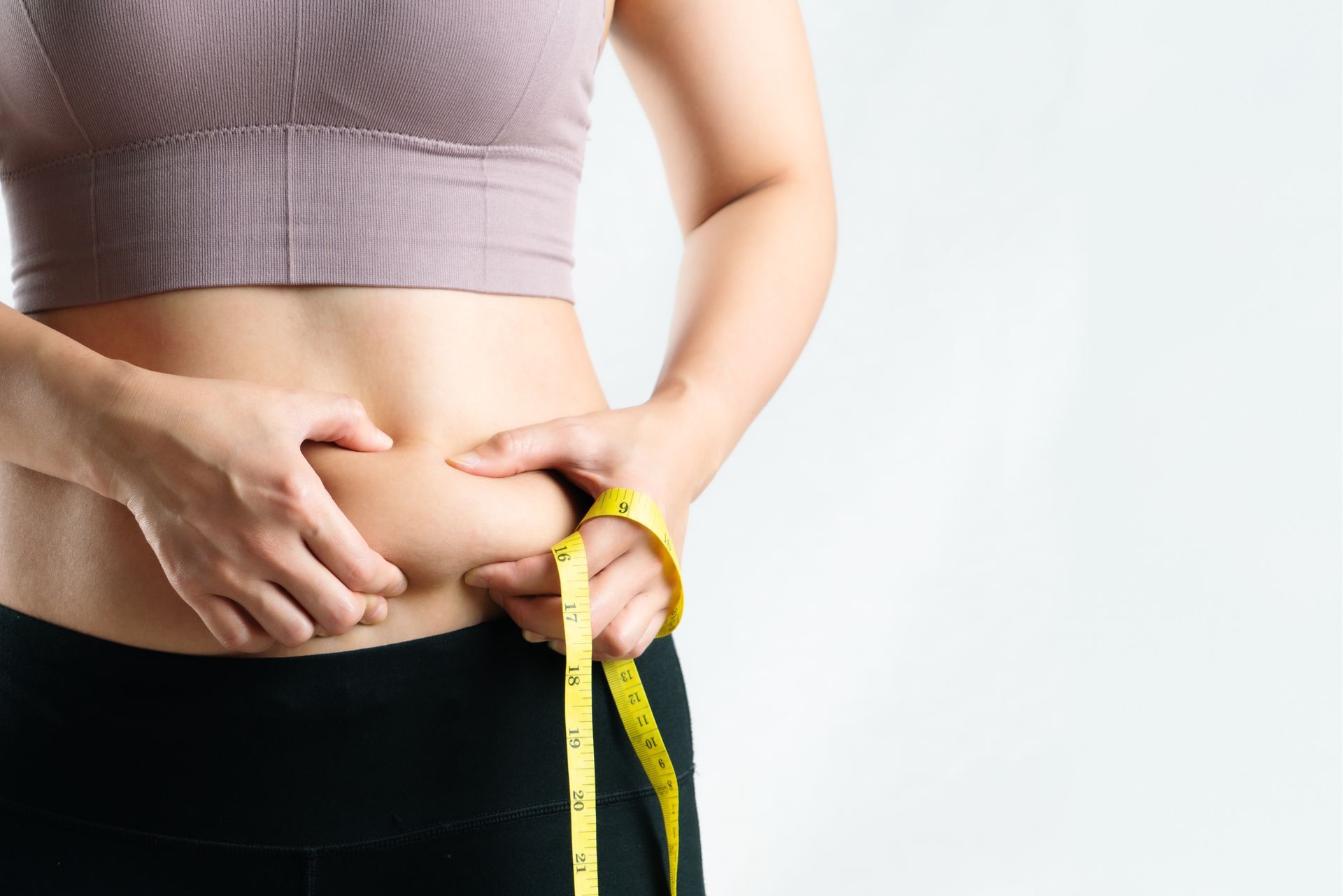 A woman is measuring her waist with a tape measure