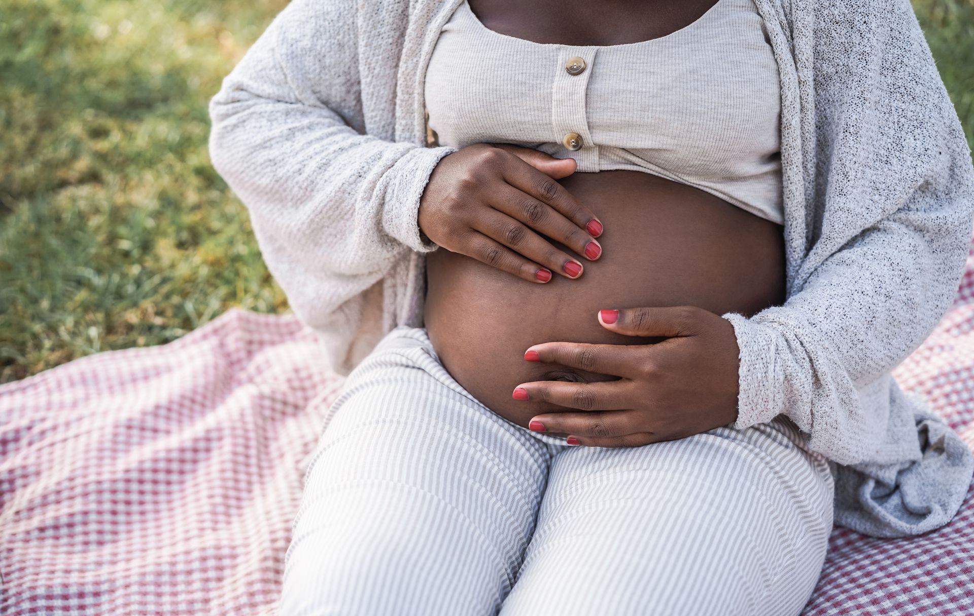 A pregnant woman with red nail polish holds her belly