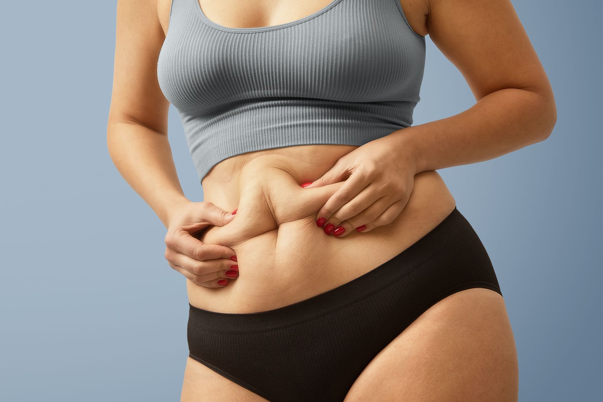 A woman with red nails is holding her stomach