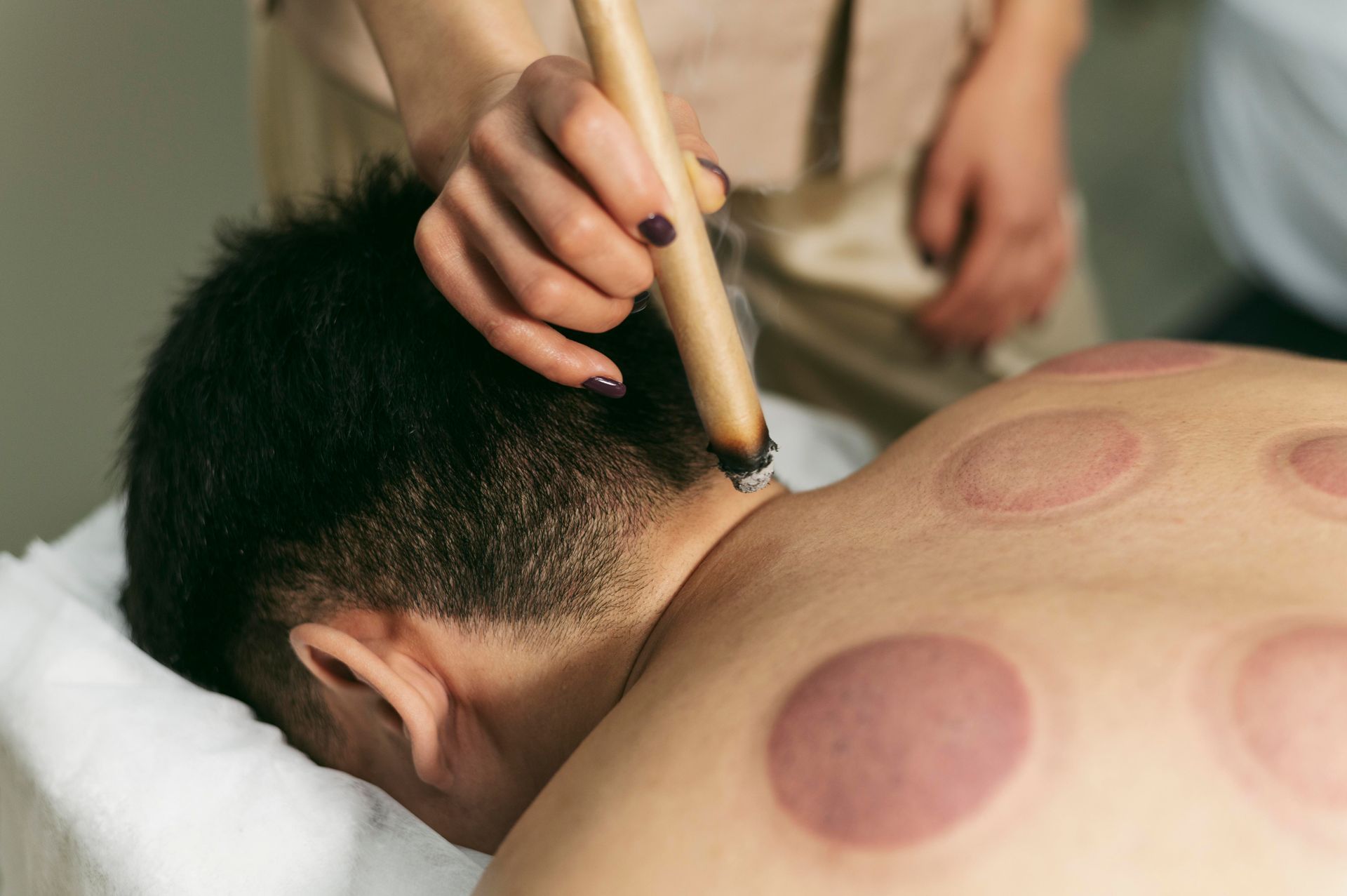 A man is getting a massage with a stick on his neck